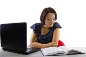 Female student taking notes on laptop while studying