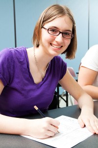 Teen girl in classroom taking test and smiling