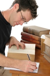 Young malelaw student taking notes from a law book at the law library