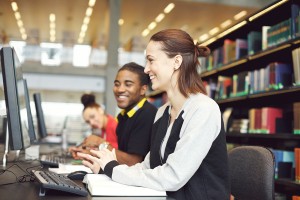 Two college students studying on desktop computers in the libary