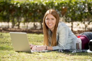 Female college student studying outdoors on laptop