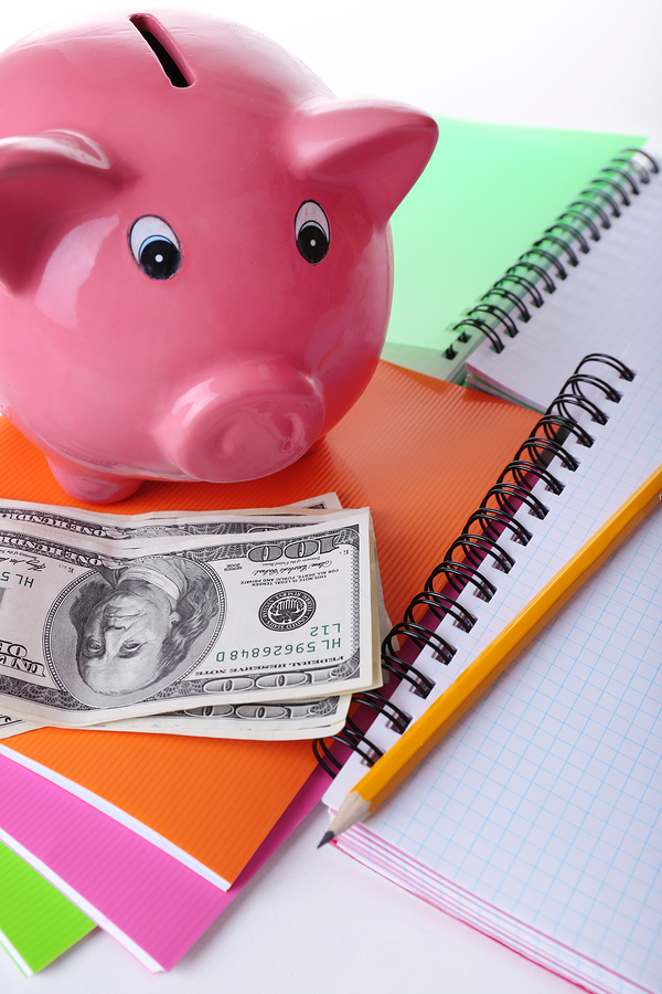 Piggy bank, cash and notebooks denoting paying for college