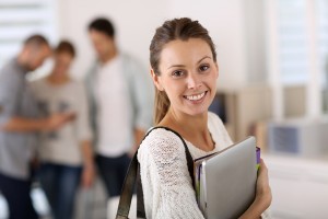 Smiling college girl holding her notebooks on the way to class